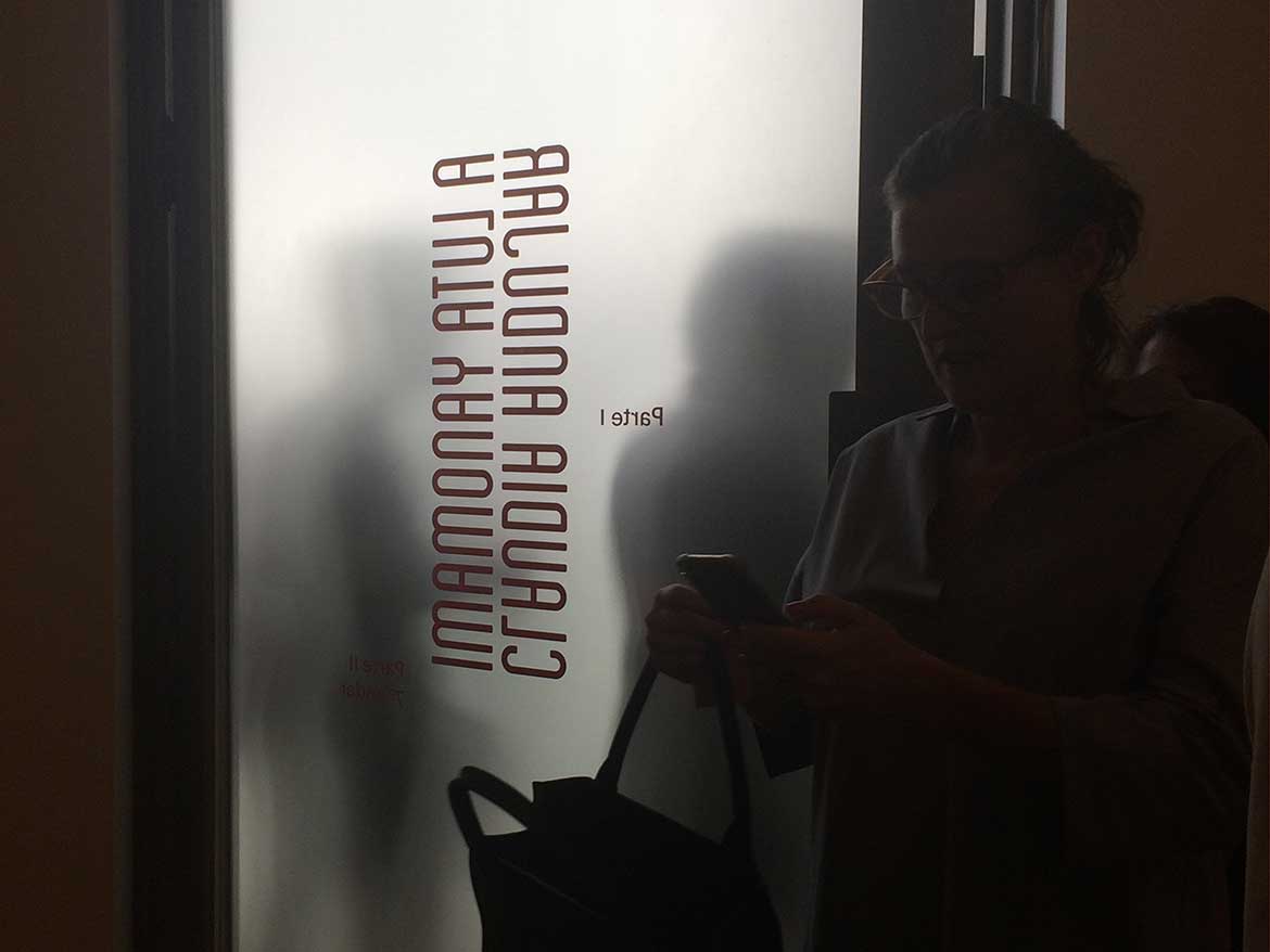 Porta translúcida mostra pessoas entrando na exposição Claudia Andujar - A luta yanomami