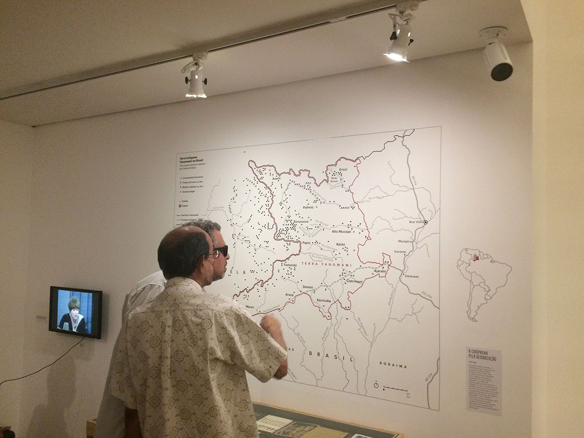 Visitantes se aproximam do mapa para analisar detalhes da imagem